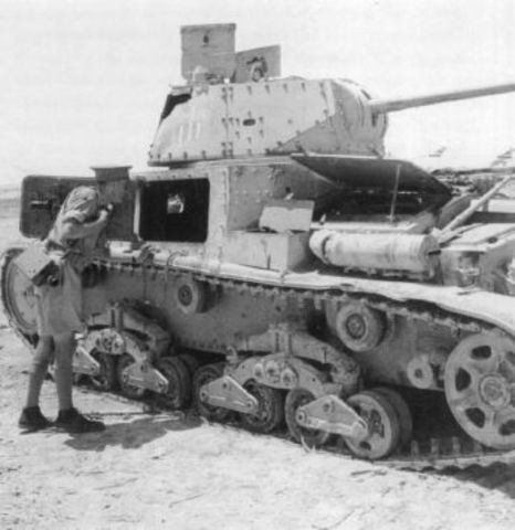 Un cámara británico mirando dentro de un tanque italiano M13 40 puesto fuera de combate
