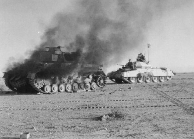 Un tanque Crusader pasa junto a un Panzer IV puesto fuera de combate en los últimos momentos de la batalla